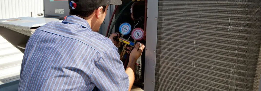 HVAC technician servicing a condenser unit in Springfield